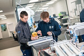 Zwei Lehrlinge arbeiten an einem Arbeitsplatz in der Lehrwerkstätte der PMS