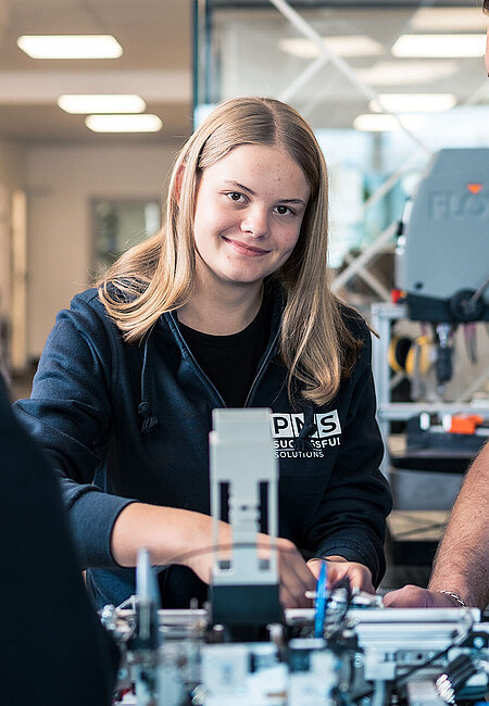 Ein Lehrmädchen arbeitet an einem Modell und der Lehrlingsausbilder beobachtet sie dabei