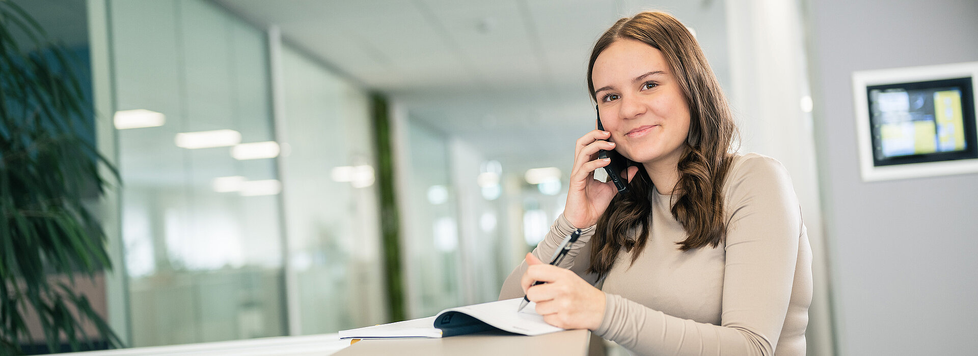 Lehrmädchen am Empfang beim Telefonieren.