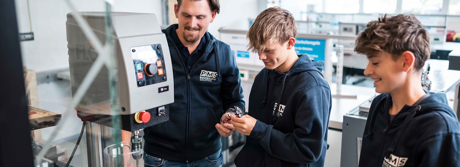 Lehrlingsausbilder mit zwei Lehrlingen in der PMS Lehrwerkstätte.